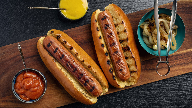 Perfectly charred hot dogs on buns with sides