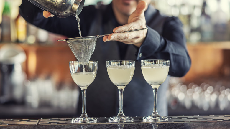 A bartender pouring gimlet-style drinks.