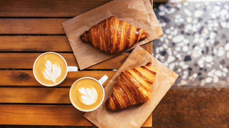 Two croissants and coffee on a wooden table