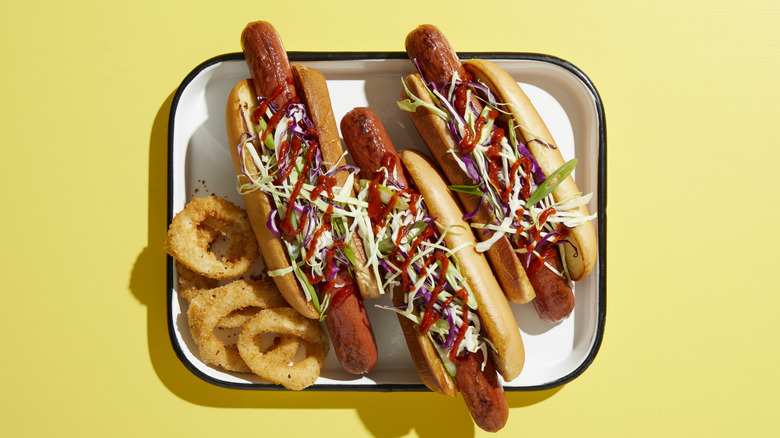 Hot dogs with slaw and onion rings on a yellow background