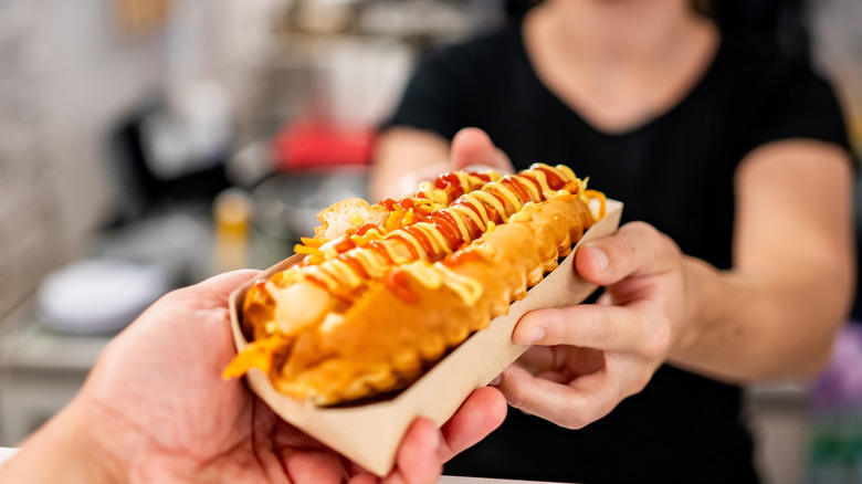 Server handing over a hot dog to a customer