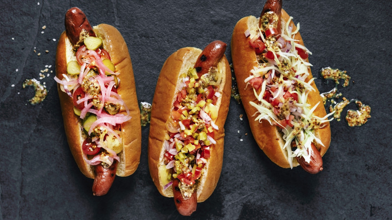 Three hot dogs with veggie toppings