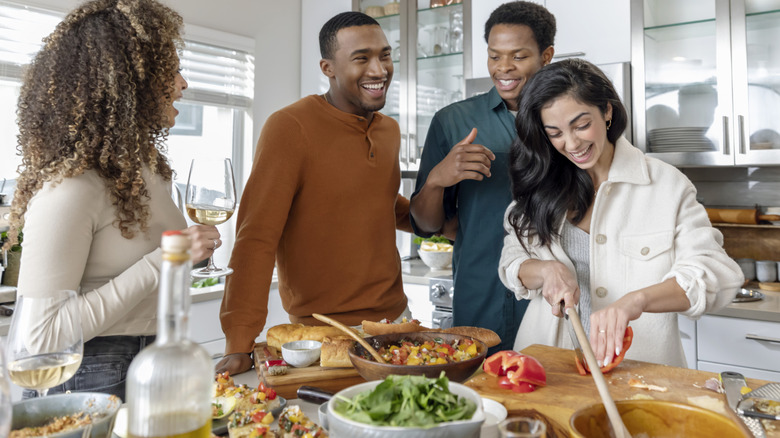 Young adults smiling and prepping food in a kitchen