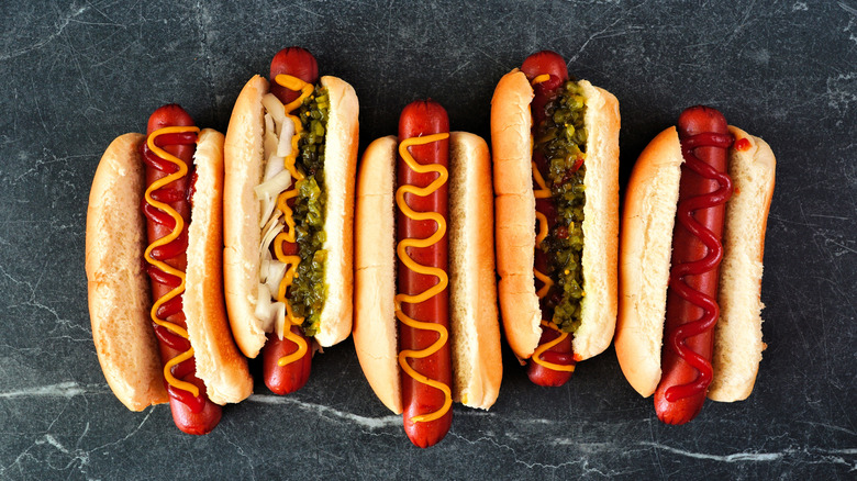 Hot dogs in buns with various toppings