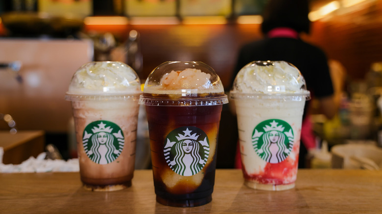 Three Starbucks specialty drinks lined up on a handoff counter