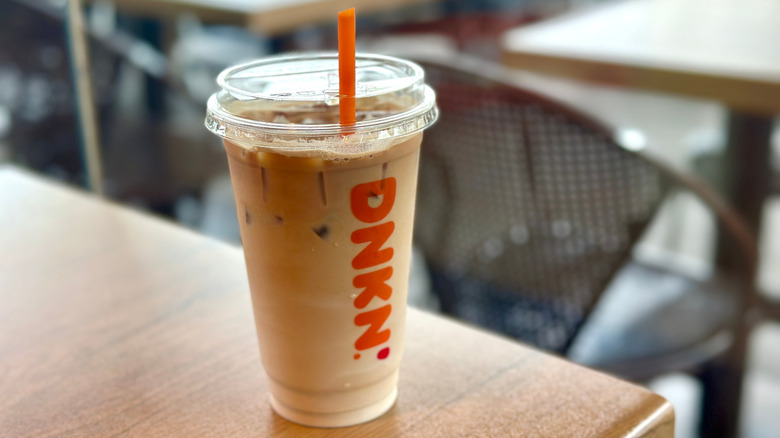 Dunkin' Donuts iced latte on wood table with orange straw