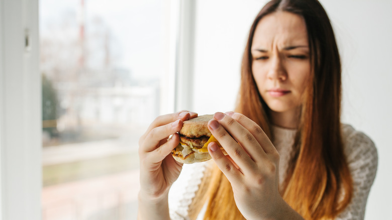 A diner looks critically at a breakfast sandwich