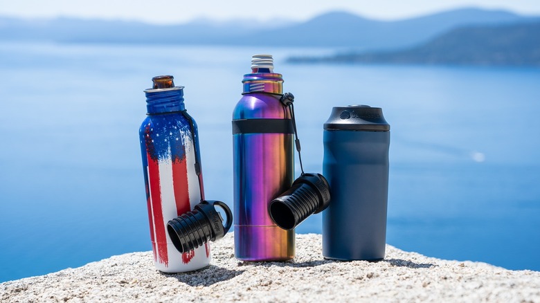 Three different BottleKeepers on a rock overlooking a large body of water