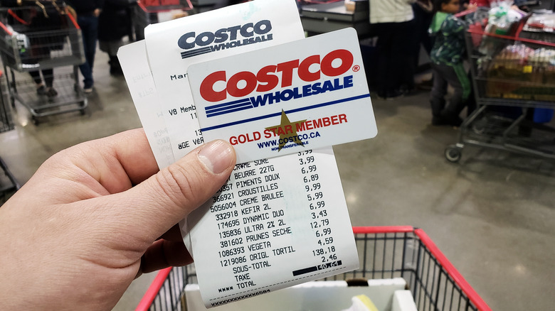 Hand holding Costco membership card and receipt