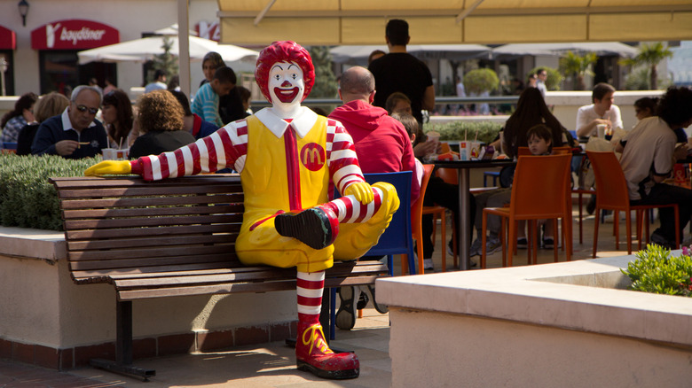 Statue of Ronald McDonald sitting on a bench