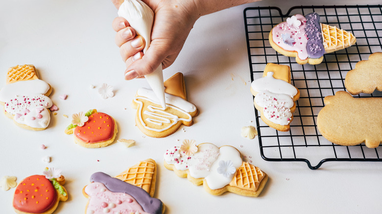 An ice cream cone-shaped sugar cookie being frosted