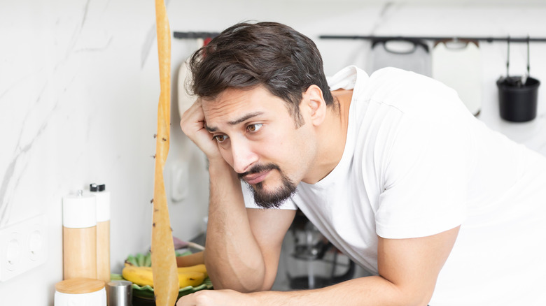 Man staring forlornly at a fly strip in his kitchen