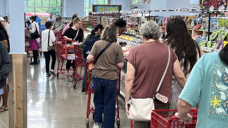 A crowd of people line the freezer aisle of a Trader Joe's store