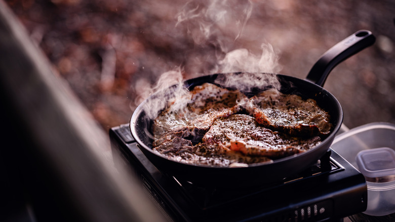 Several thin steaks curling in a pan