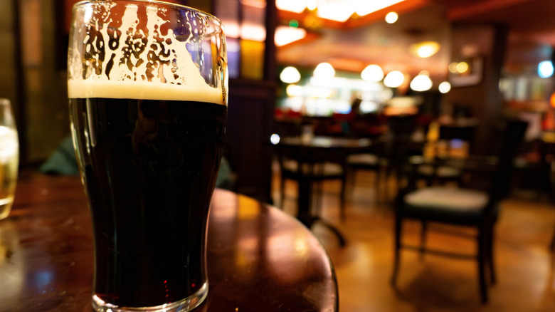 A pint glass of Irish stout on a table in a pub