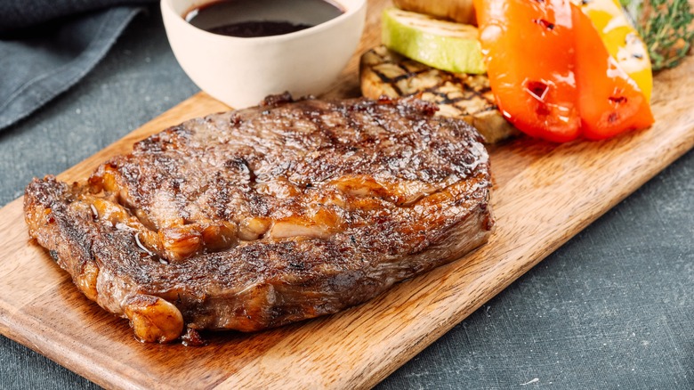 Steak on a wooden board with grilled veggies
