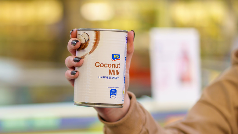 Someone holds up a can of coconut milk