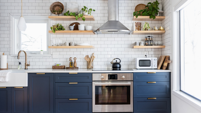 A kitchen with dark blue cabinets and white subway tiles