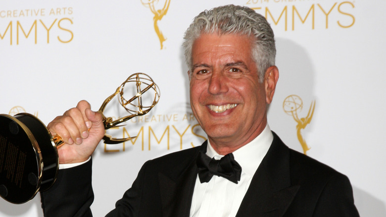 Anthony Bourdain holding an emmy.