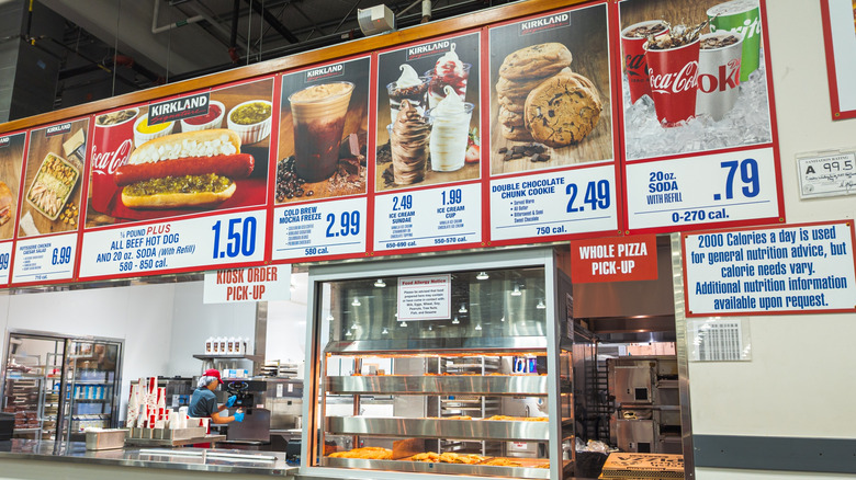 A Costco food court menu hangs overhead