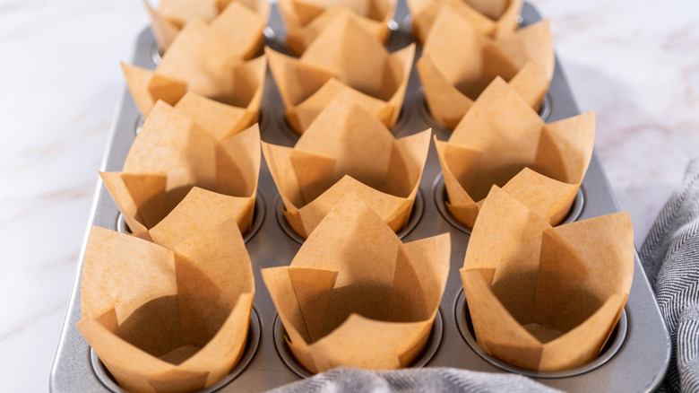 A muffin tray lined with parchment paper muffin liners