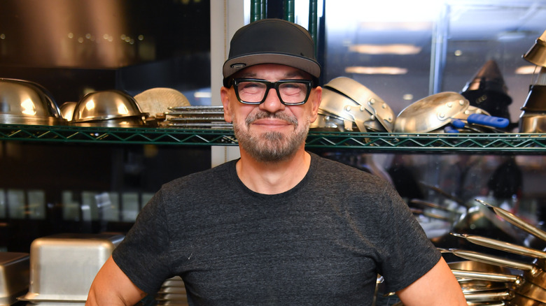 Michael Symon smiling in front of cooking equipment