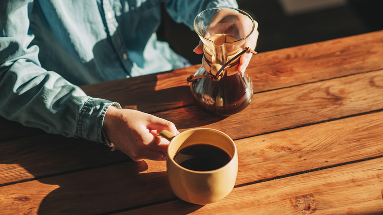 A man sits at a table with a pour over coffee