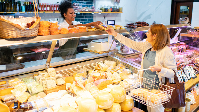 a shopper buys artisan cheese from a delicatessen