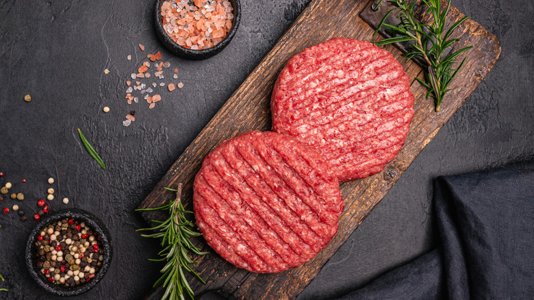 burger patties on a dark background with peppercorns