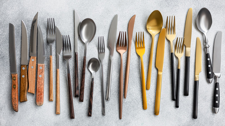 Silverware lined up in a row on a gray surface.