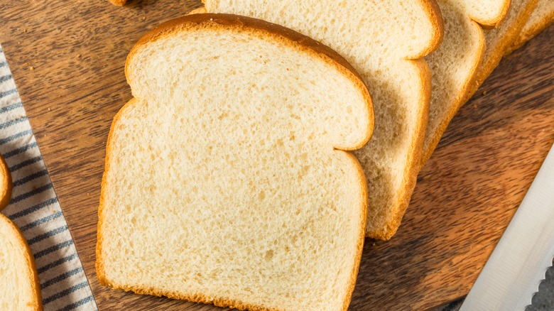 White sandwich bread on wooden cutting board