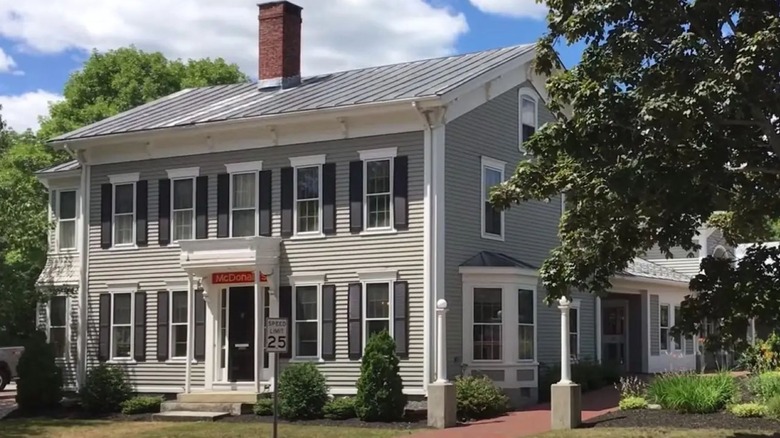 Gray Colonial-looking house with white trim with a small red McDonald's sign over the door