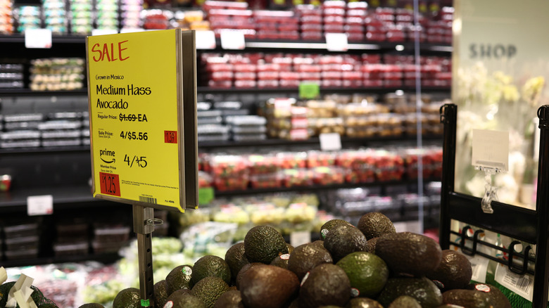 A pile of avocados sits under a sale sign in a Whole Foods store