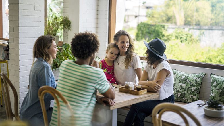 Group of adults sitting at a table at a restaurant with a child on the lap of one adult.