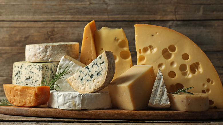 An array of different cheeses laid out, including blues, bries, gouda, and cheddar