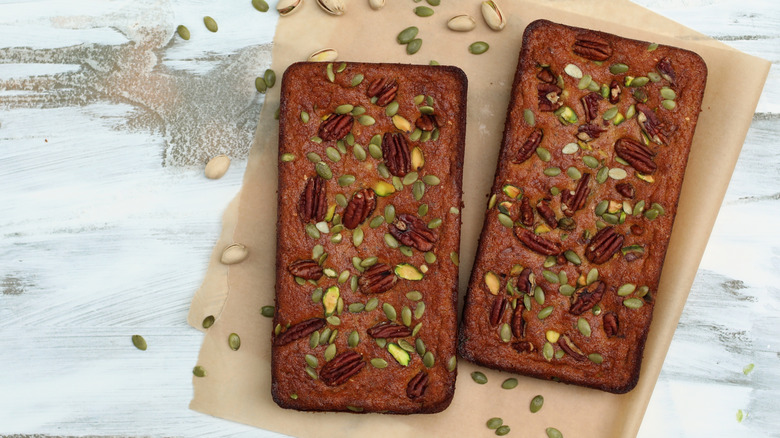 Two loaves of banana pumpkin bread, topped with nuts and seeds