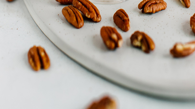 praline ice cream in a clear bowl surrounded by pecans