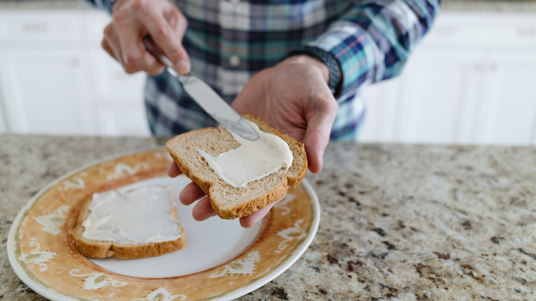Man spreading mayo on a piece of bread