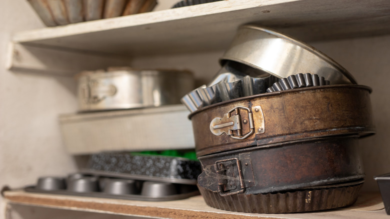 Pie and cake pans sit stacked on top of each other on a pantry shelf
