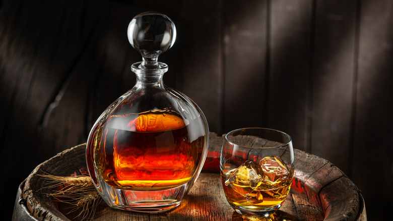 Glass decanter full of whiskey next to a glass of whiskey