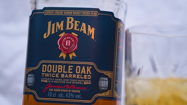 Close up of Jim Beam Double Oak label, a glass of whiskey behind