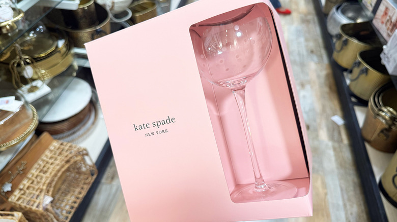A hand holds up a pack of Kate Spade wine glasses
