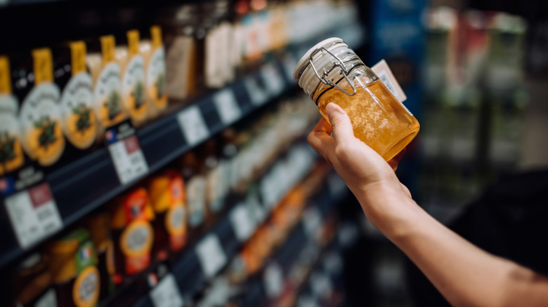 Shopper holding honey jar at store