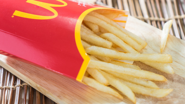 McDonald's fries spill out of their sleeve onto a wooden surface
