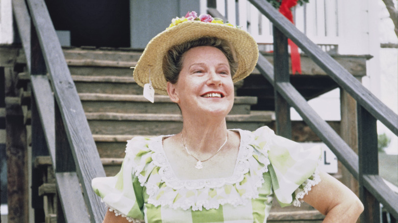 Minnie Pearl wearing straw hat with tag hanging down in a green and white checkered dress