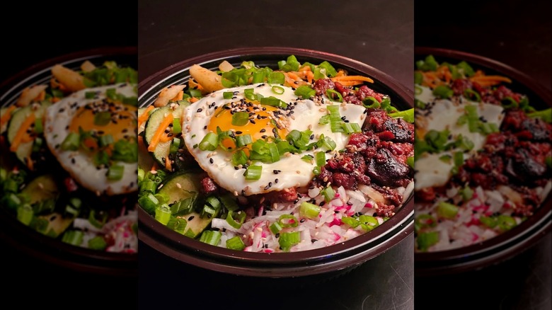 Egg and green onion dish in a brown bowl placed on a brown table