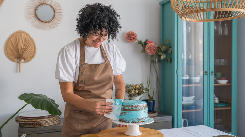 A person frosting a cake with blue icing.