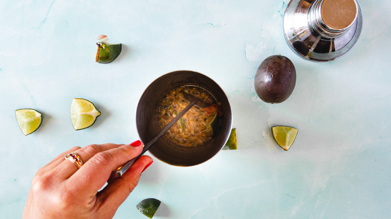 hand muddling passion fruit and lime