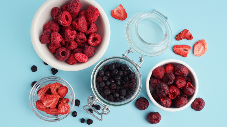 Bowls of freeze dried berries on blue background