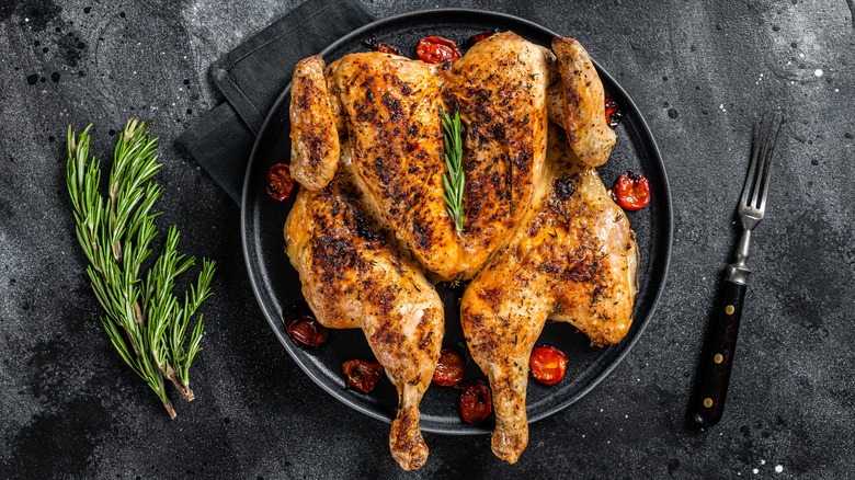 a spatchcocked, roasted chicken served in pan with herbs